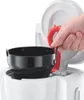 A close-up shot of a person's hand holding a black coffee filter basket over a white coffee maker. Náhľad obrázku produktu