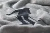 A close-up shot of a grey blanket with a black silhouette of a skier printed on it. Produktbild-Vorschau
