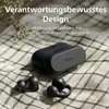 A pair of black wireless earbuds and their charging case are placed on a checkered cloth, with a sprig of greenery in the upper left corner. Voir les images du produit