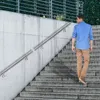 A man walks up a concrete staircase with a metal handrail. Náhled obrázku produktu