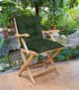 A green cushion on a wooden chair in a garden setting with plants and rocks. Náhled obrázku produktu