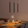 A dining table set for a meal, with three pendant lights hanging above. Produktbild-Vorschau