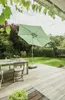 A patio scene with a table, chairs, and a large umbrella. Produktbild-Vorschau