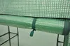 A close-up view of a rolled-up green material secured by a dark green strap, attached to a horizontal bar within a greenhouse structure. Náhled obrázku produktu