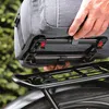 A person is attaching a gray bag to a black bicycle rack. Podgląd zdjęcia produktu