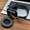 A pair of black headphones and a detached ear cushion are placed on a wooden surface next to a laptop. Voir les images du produit