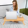 A woman is working on her laptop on a bed, with a small table in front of her holding the laptop and a cup of coffee. Produktbild-Vorschau