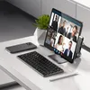 A desk setup with a tablet displaying a video conference, a keyboard, and a smartphone. Náhled obrázku produktu