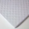 A close-up, angled view of a white quilted mattress protector on a white background. Anteprima dell’immagine prodotto