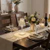 A dining table set for a meal with a decorative lamp, flowers, and wine. Produktbild-Vorschau
