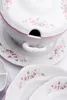 A close-up shot of a white porcelain soup tureen and plates decorated with pink roses. Voir les images du produit