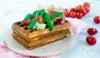 A waffle sandwich with ham, arugula, and tomatoes on a plate, with cherry tomatoes in the background. Anteprima dell’immagine prodotto