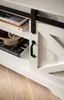 A close-up view of a white TV cabinet with a sliding barn door mechanism and a black handle. Náhľad obrázku produktu