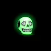 A glow-in-the-dark skull charm with crystal accents, set against a black background. Produktbild-Vorschau