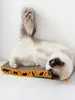A cat is lying on its back on a scratching pad. Produktbild-Vorschau