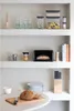 Kitchen shelves with various items including food storage containers, glasses, a bread box, a bread loaf, plates, and knives. Podgląd zdjęcia produktu