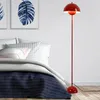 A red floor lamp stands next to a bed in a bedroom. Anteprima dell’immagine prodotto