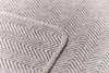 A close-up view of a blanket with a herringbone pattern and a stitched edge. Produktbild-Vorschau