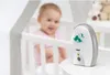 A baby is in a crib, and a baby monitor is on a table next to it. Produktbild-Vorschau