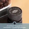 Close-up of a coffee grinder's adjustment dial with coffee beans in the background and marketing text at the bottom. Produktbild-Vorschau