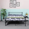 A bedroom scene with a metal bed frame, bedding, a plant, and framed pictures on the wall. Voir les images du produit