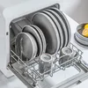A dishwasher rack filled with gray plates, bowls, and mugs, with two lemons in a bowl in the background. Náhled obrázku produktu
