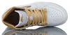 A top-down view of a white and gold Nike Air Jordan 1 Retro High sneaker, resting on a reflective surface. Podgląd zdjęcia produktu