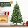 A decorated Christmas tree next to a fireplace with stockings. Produktbild-Vorschau