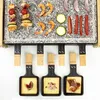 A raclette grill with food items arranged on the granite stone surface and in the individual pans. Produktbild-Vorschau