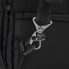 A close-up of a black backpack strap and a metal clasp. Voir les images du produit