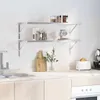 A kitchen scene with two stainless steel shelves mounted on a tiled wall. Produktbild-Vorschau