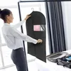 A woman is holding a garment bag in a bedroom. Anteprima dell’immagine prodotto