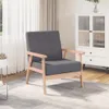 A dark gray fabric armchair with wooden legs is placed on a light gray checkered rug in a room with sheer white curtains and a white cabinet in the background. Voir les images du produit