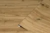 A roll of wood-look adhesive film is partially unrolled on a surface of the same material. Náhled obrázku produktu
