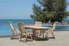 A wooden table and chairs set by a swimming pool with the ocean in the background. Produktbild-Vorschau