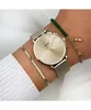 A person's wrist wearing a gold Cluse watch and two bracelets. Voir les images du produit