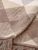 A close-up view of a folded blanket with a plaid pattern. Produktbild-Vorschau