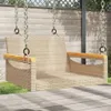 A beige poly rattan hanging chair is shown outdoors on a wooden deck, with grass and a wooden fence in the background. Náhled obrázku produktu