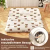 A folded mattress with a bear pattern is shown on a wooden floor, with text overlays and a circular inset showing a hand putting laundry into a washing machine. Náhled obrázku produktu