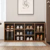 A shoe rack with storage compartments and a padded top for seating, placed in an entryway with a framed picture above it. Anteprima dell’immagine prodotto