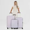 A woman stands behind three suitcases of varying sizes. Produktbild-Vorschau