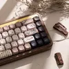 A close-up shot of a mechanical keyboard with a wooden case and decorative keycaps, placed on a textured surface with dried plant sprigs and pieces of wood. Produktbild-Vorschau