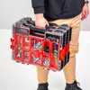 A person is holding a red and black organizer box filled with tools and hardware. Náhled obrázku produktu
