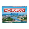 The image shows the front of a Monopoly board game box featuring a city skyline and river. Produktbild-Vorschau