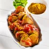A dish of currywurst with sauce and curry powder, served in a white dish with a sprig of parsley and a small bowl of curry powder in the background. Produktbild-Vorschau