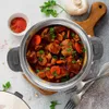 A top-down view of a stew in a pot, with ingredients and utensils around it. Voir les images du produit