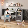 A young boy is sitting at a child's desk, reading a book. The desk has shelves and a drawer, and is decorated with chalk drawings on the wall behind it. There are also toys on the floor in front of the desk. Podgląd zdjęcia produktu