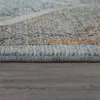 A close-up, low-angle view of the edge of a rug with a textured surface and a patterned design. The rug is placed on a wooden floor. Produktbild-Vorschau