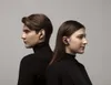 A man and a woman are shown from the side, both wearing black turtlenecks and black earbuds. They are positioned back-to-back against a plain gray background. Podgląd zdjęcia produktu