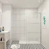 A modern bathroom with a walk-in shower, vanity, and patterned floor tiles. Produktbild-Vorschau